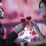 Young couple sharing a glass of red wine in restaurant, celebrat